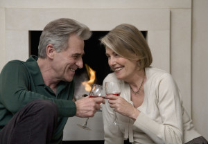 Senior couple sipping win by fireplace